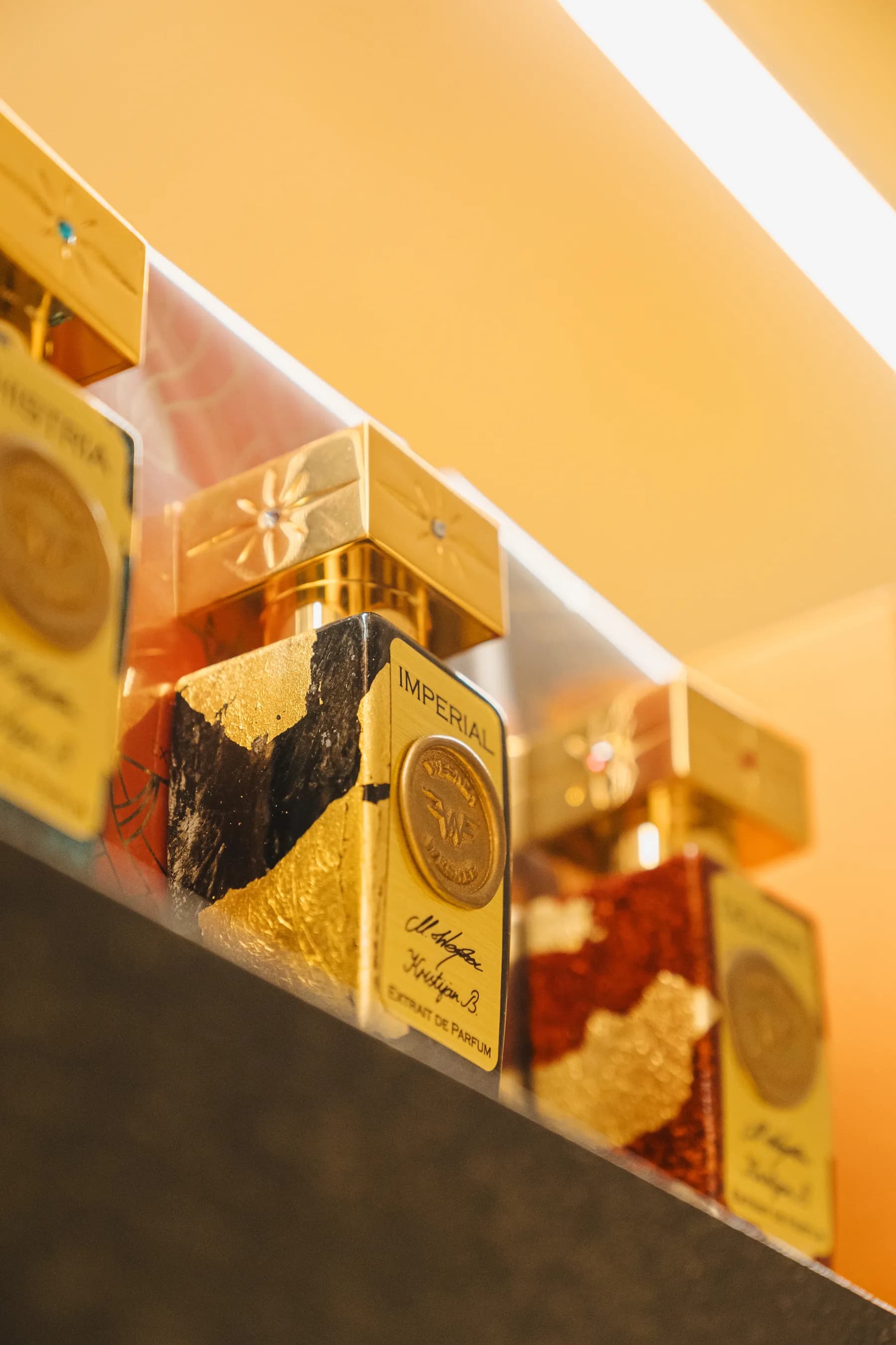 Flaconi dorati su una mensola illuminata in boutique.