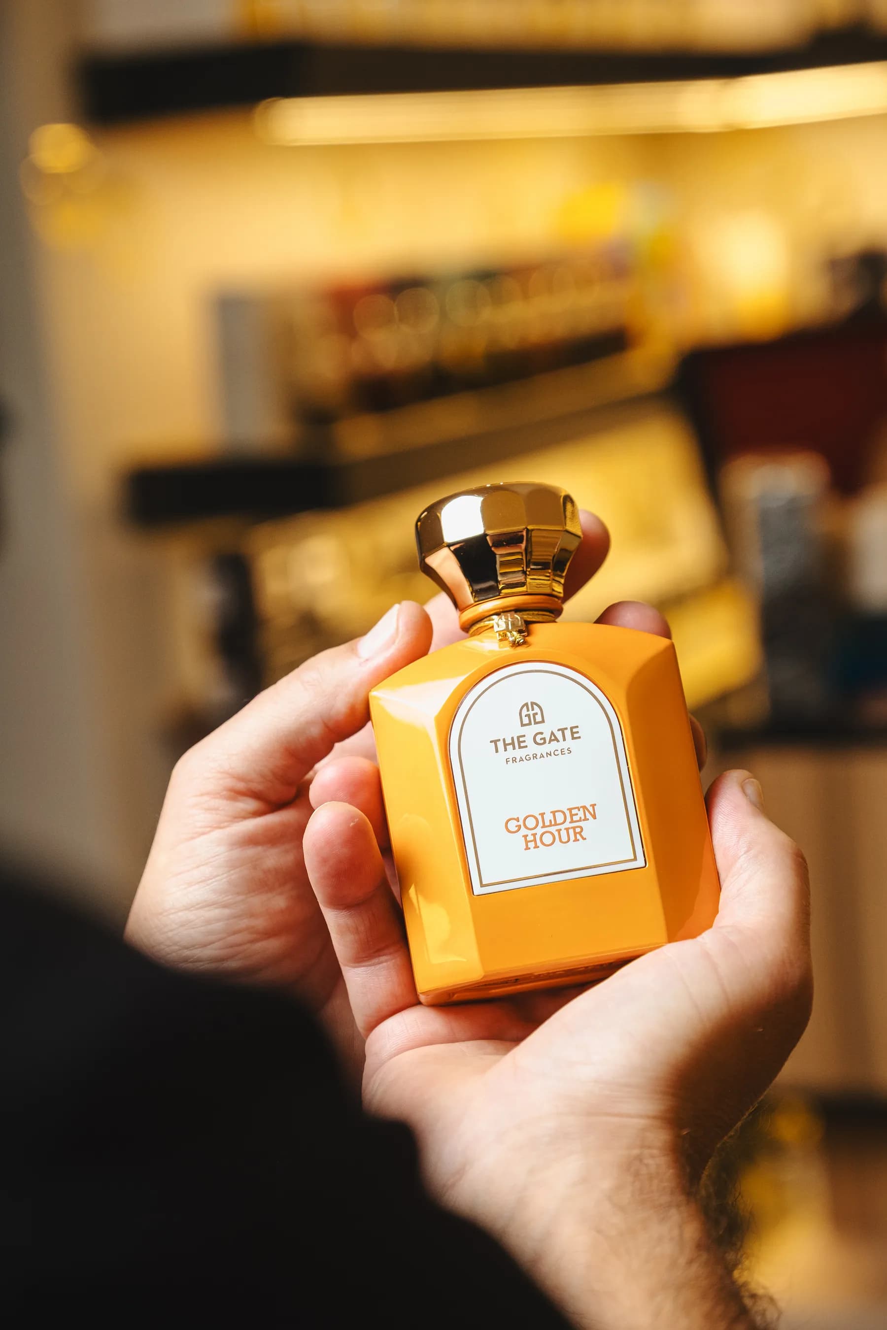 Flacone arancione tenuto in mano con la boutique sfocata sullo sfondo.