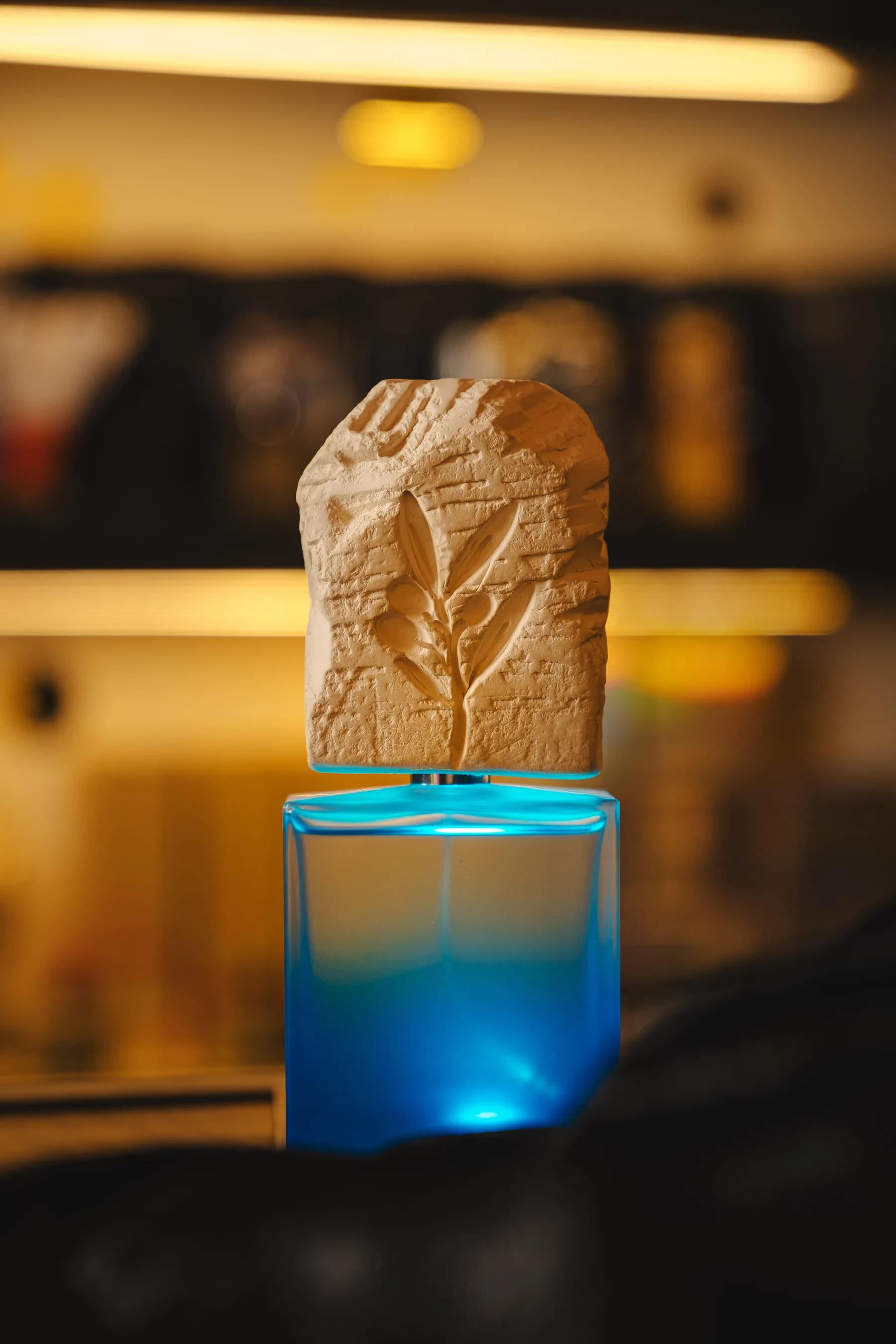 Flacone azzurro con scultura in pietra illuminata nella boutique.
