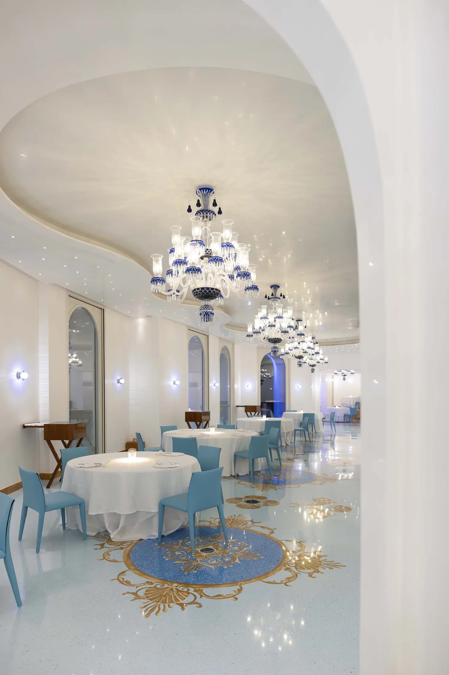 Sala di Casanova con arcate bianche e lampadario in vetro blu.