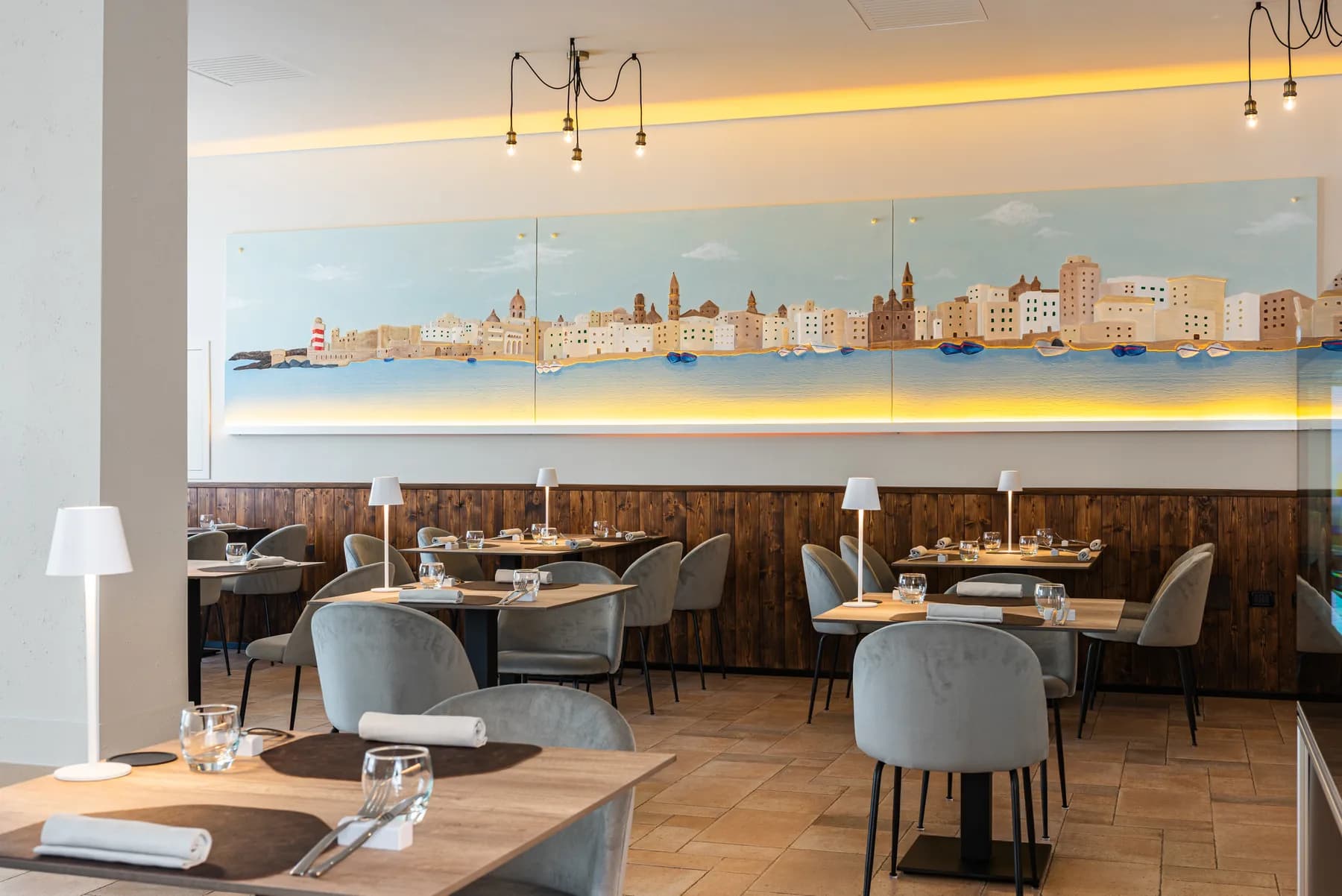 Sala di DDO JÈ con il murales dello skyline di Monopoli.