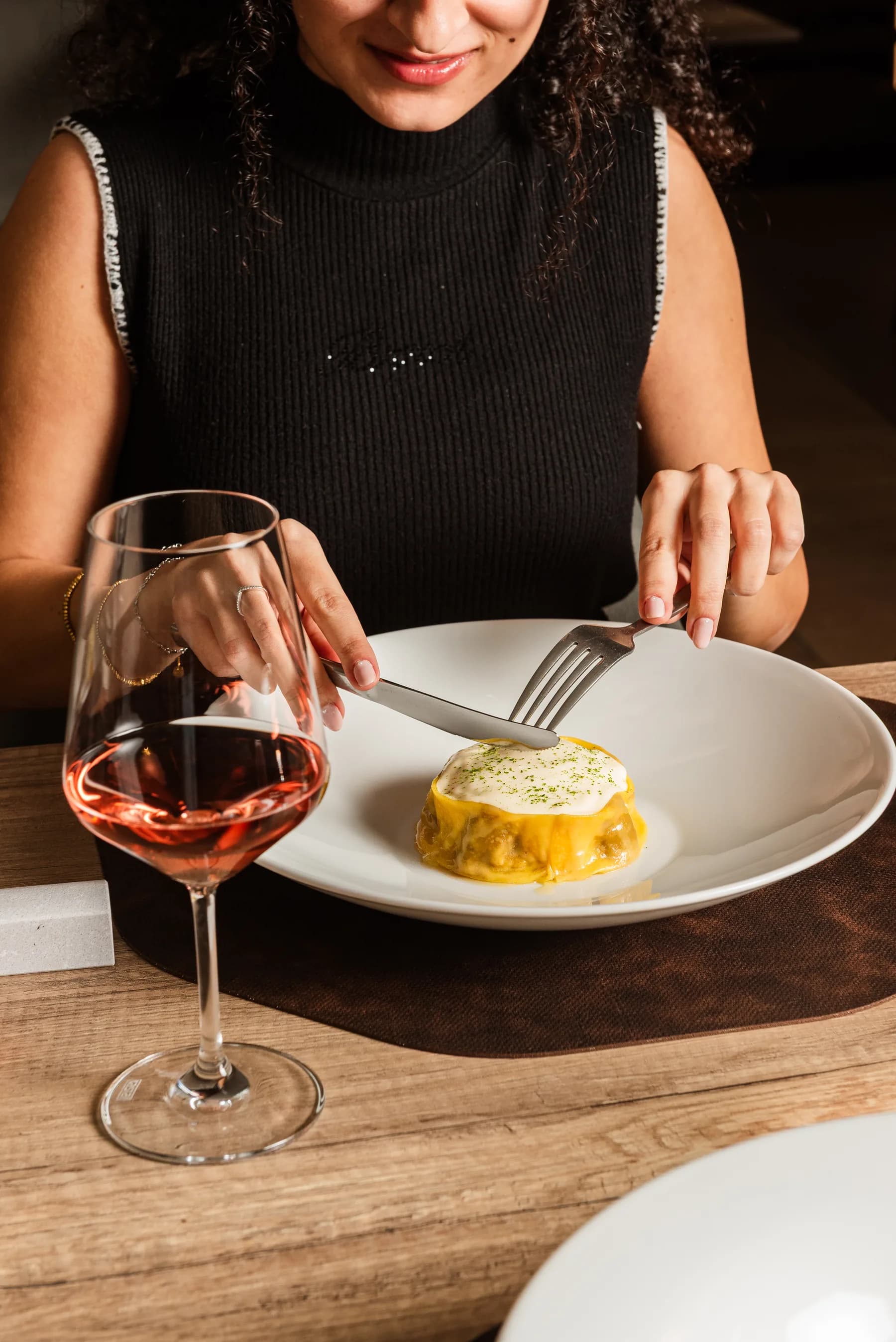 Ospite con un calice di rosato davanti a un piatto di uovo e crema di zucca.