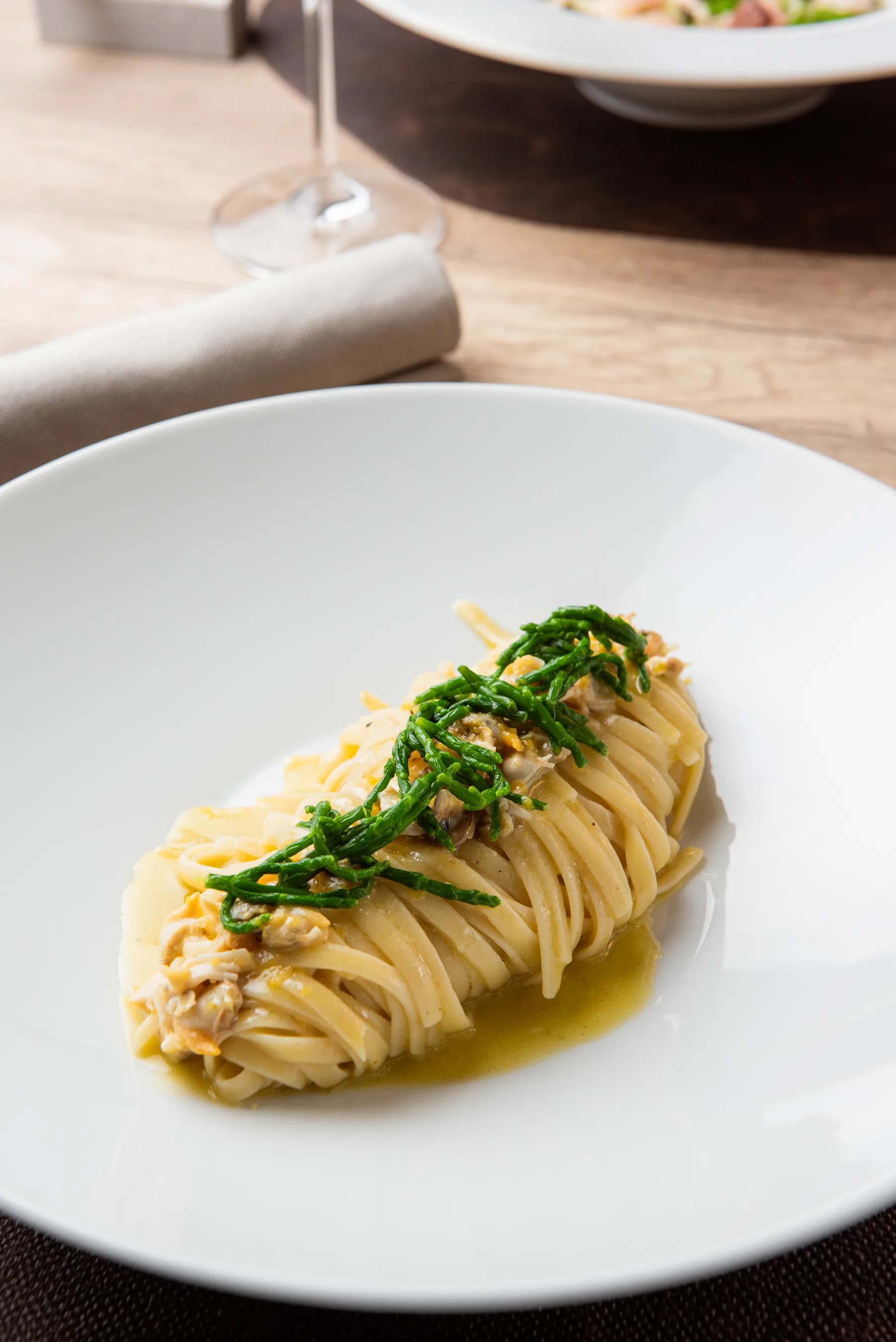 Spaghetti con salicornia su piatto bianco.