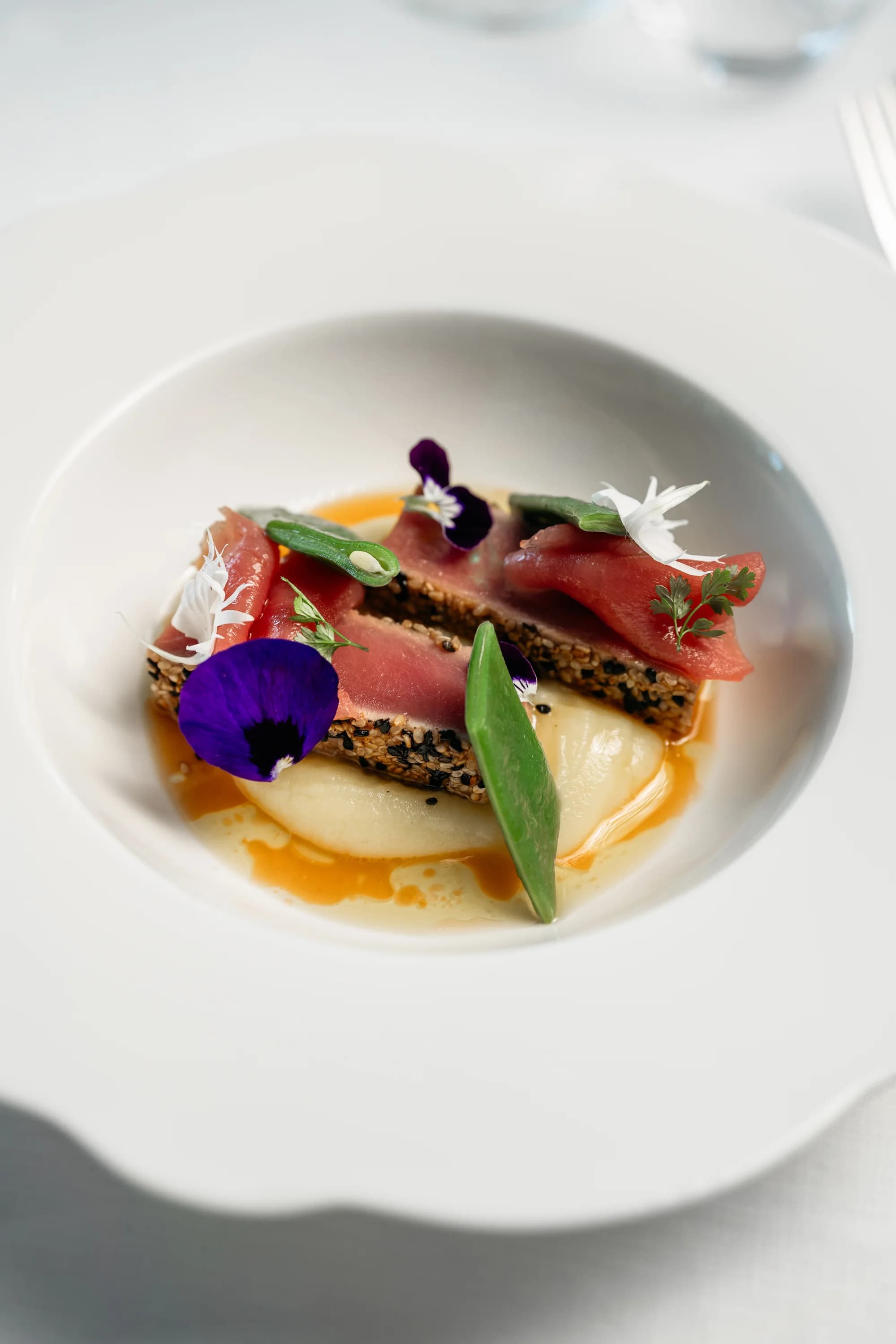 Piatto fine dining di Grotta Palazzese con tonno e fiori eduli.