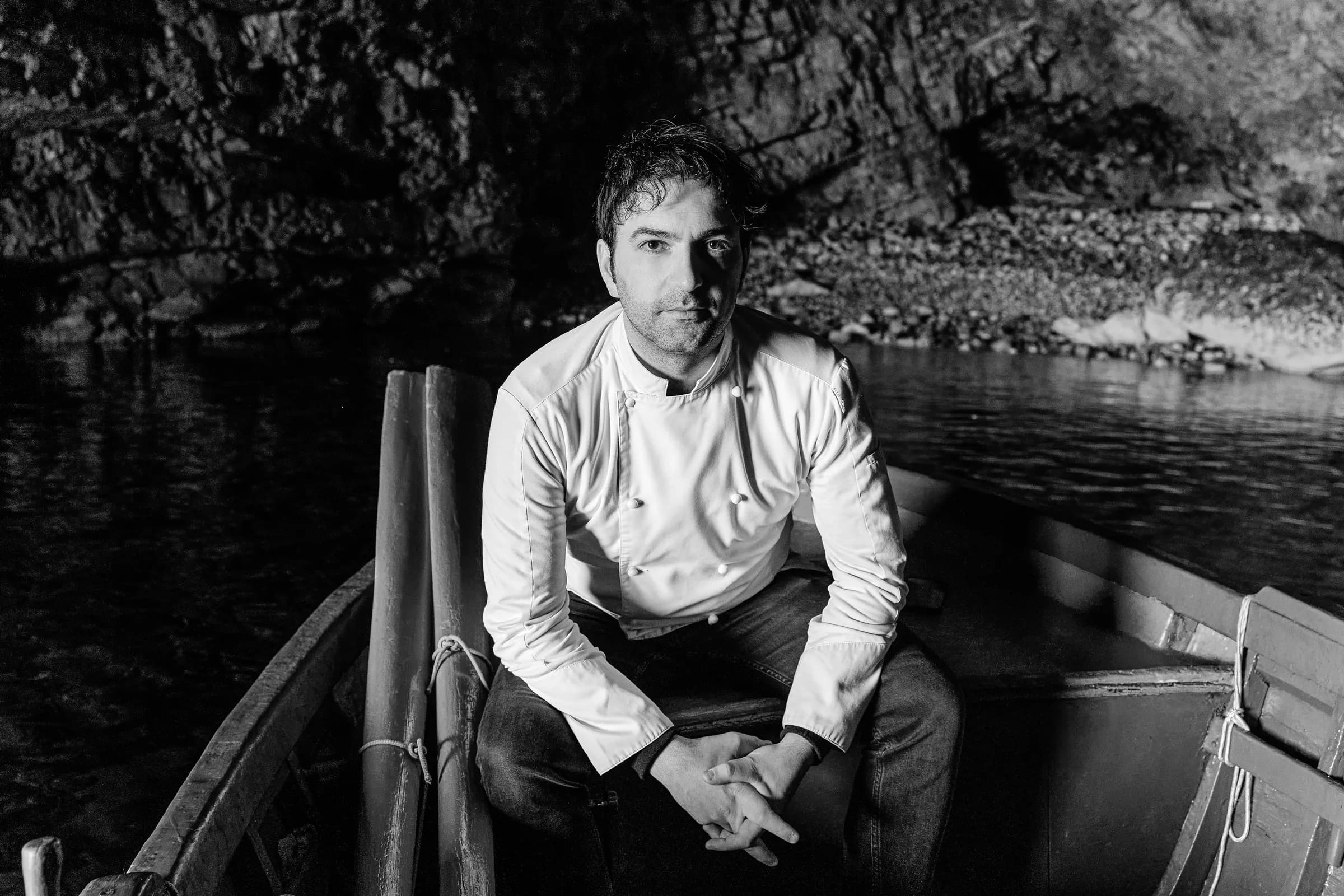 Ritratto in bianco e nero dello chef in barca sotto la grotta.