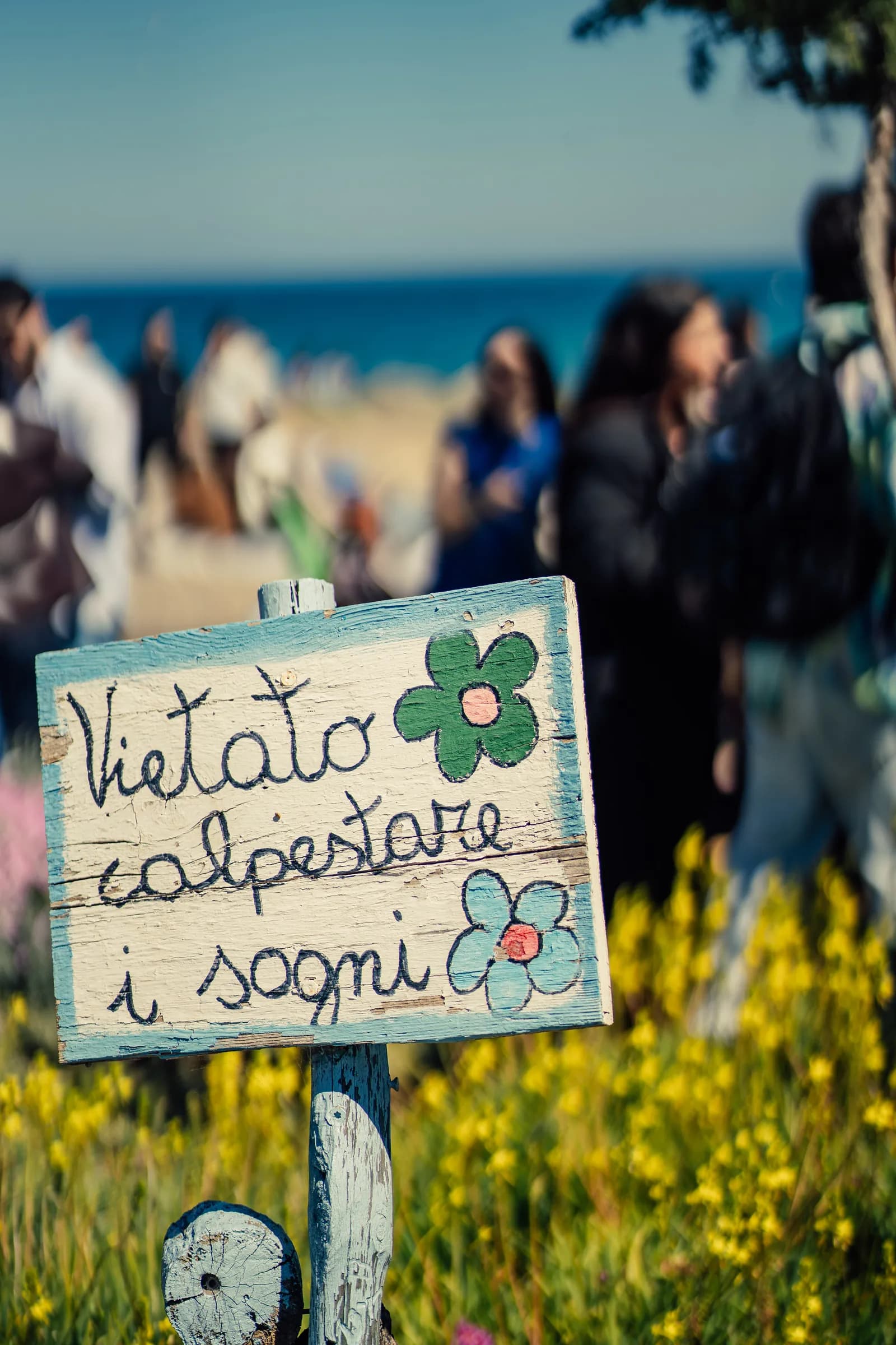 Cartello «Vietato calpestare i sogni» tra i fiori dell'Archeolido.