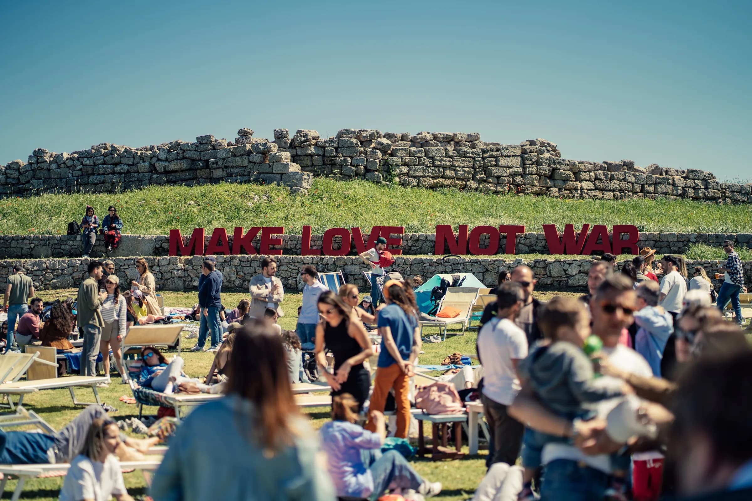 Pubblico davanti alla scritta Make Love Not War all'Archeolido di Egnazia.