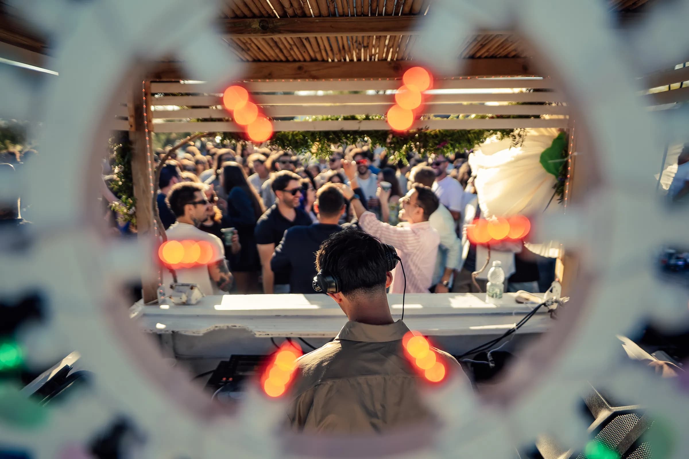 Dj set e pubblico visti attraverso una decorazione circolare.