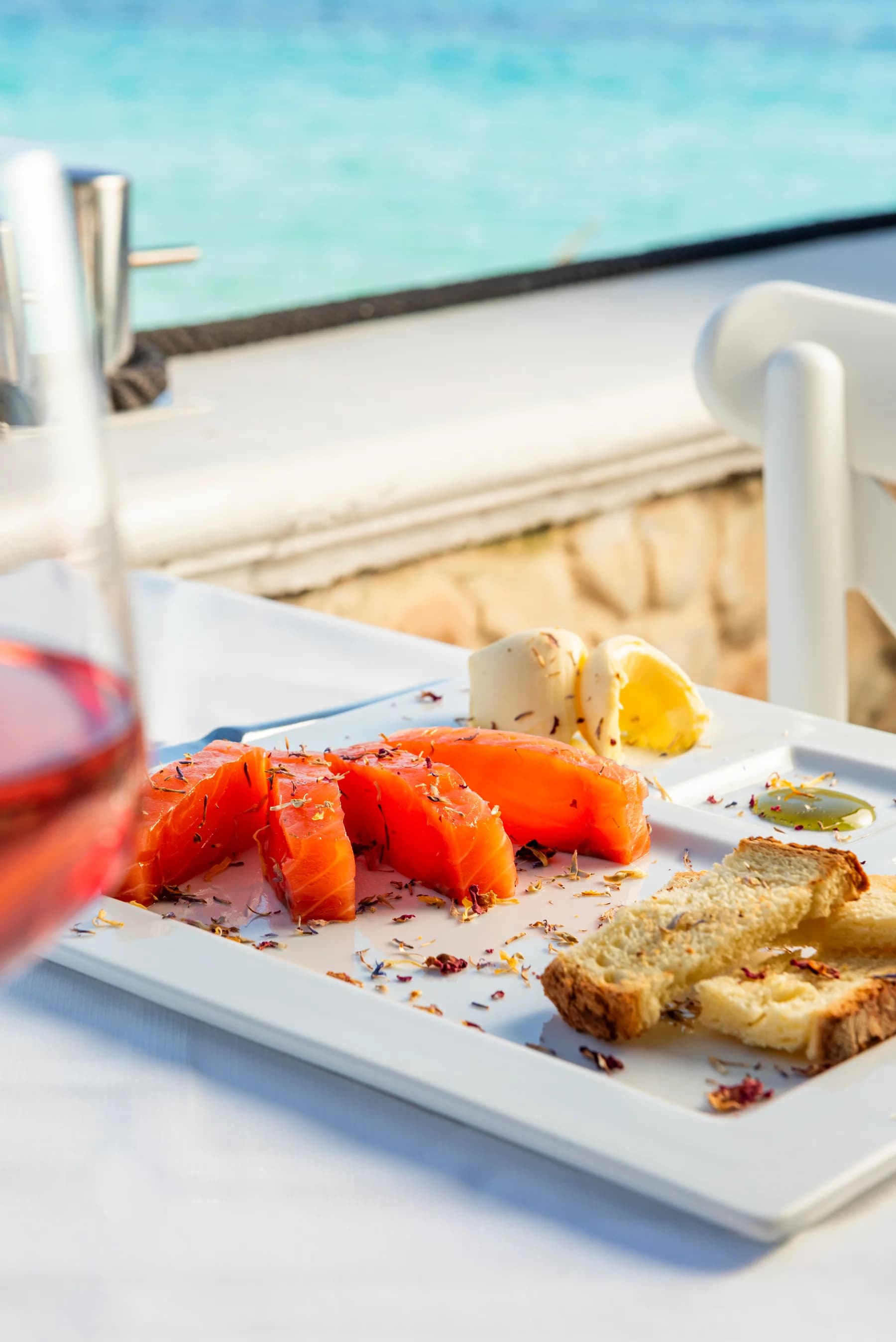 Selezione di crudi e antipasti su piatto bianco con calice di vino.