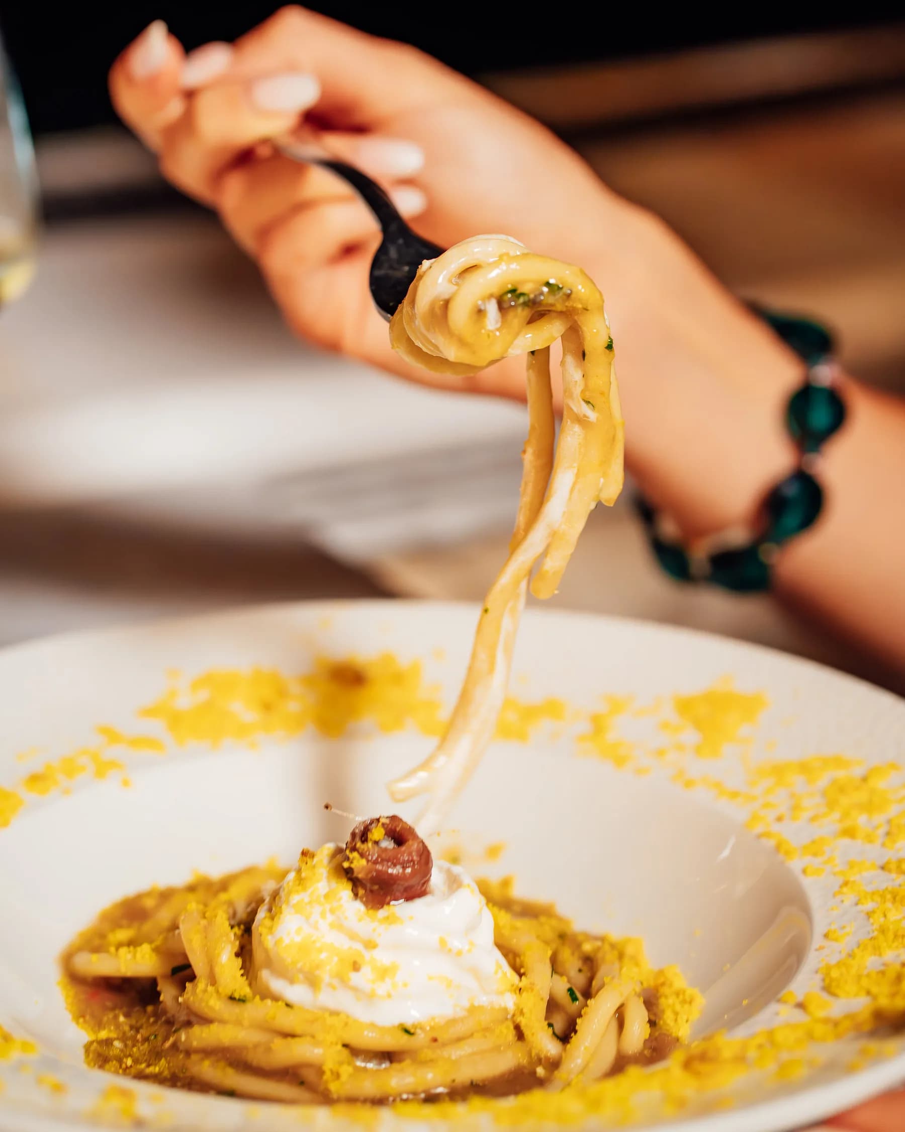 Spaghetti avvolti sulla forchetta con stracciatella e acciuga.